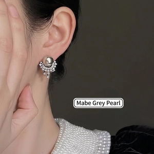 Elegant silver earrings featuring grey pearls and fan-shaped rhinestones on a female model