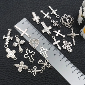 Assorted silver cross pendants for DIY jewelry making shown with ruler for size reference