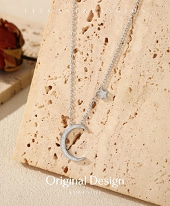 Macro shot of silver crescent moon and star pendant with pave zircon stones
