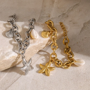 Detailed close-up of 18k gold and silver starfish shell charms on a chunky link chain