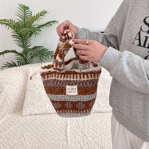 Détail d'un sac cabas en peluche avec étiquette colorée et motif jacquard géométrique