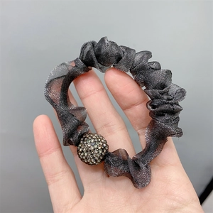 Detail of dark grey pleated mesh hair tie featuring a sparkling rhinestone-studded ball bead