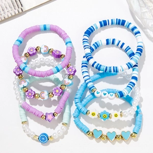 Colorful beaded bracelet set featuring clay discs, pearls and mixed charms on white base