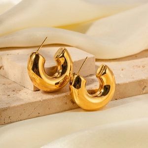 Detail view of 18K gold plated chunky hollow C-shaped earrings on light silk background