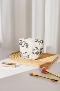 Detail of floral embroidery and gold flower zipper on linen toiletry bag with woven label