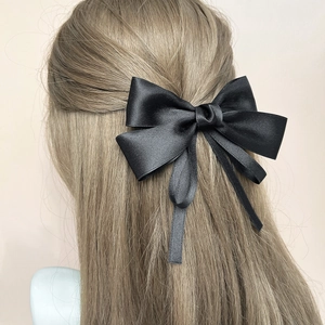 Elegant black satin bow hair clip shown from behind on hair for a stylish hair accessory look