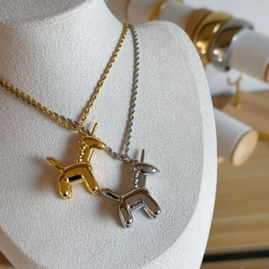Macro shot of mirror-polished gold and silver balloon unicorn pendants on twist chains