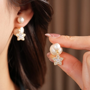 Detailed view of 18K gold plated star earrings with white pearls and sparkling zircons