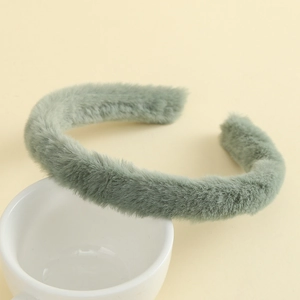 Detailed texture of a soft mint green plush headband on a white ceramic cup