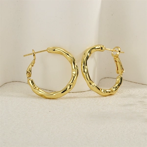 Detailed macro view of gold earrings with unique hammered texture and irregular surface