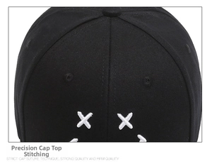Detail of white cross embroidery and stitching on a black cotton baseball cap top