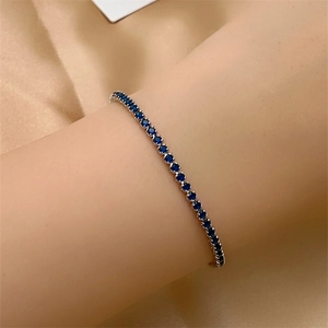 Classic single row tennis bracelet with round blue zircons on champagne silk background