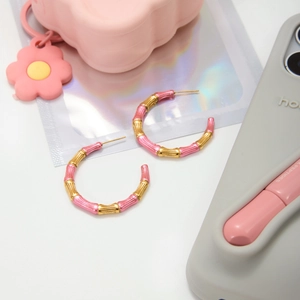 Detail of pink and gold bamboo-jointed hoop earrings showing fine enamel texture