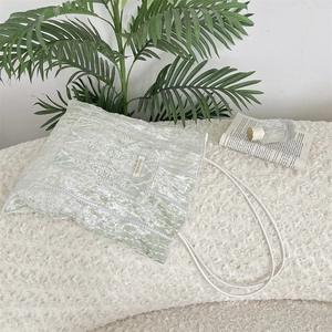 Close-up of mint green velvet tote bag with white lace embroidery and fabric brand label