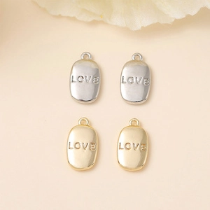 Detailed view of oval metal charms featuring LOVE engraving for DIY jewelry making