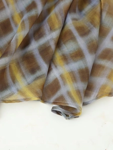 Close-up of lightweight plaid fabric with soft brown and yellow tie-dye patterns