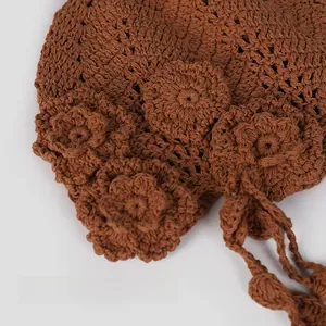 Close-up of handmade crochet flower details on the brim of a brown knit beret hat