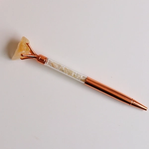 Detail of rose gold crystal pen with raw yellow stone top and filled gravel tube