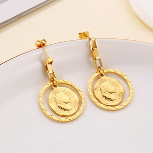 Macro shot of vintage gold coin earrings with Swiss relief detail on white ceramic base