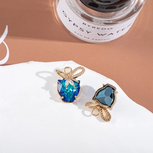 Close-up of golden bow and heart crystal earrings displayed on white stone props