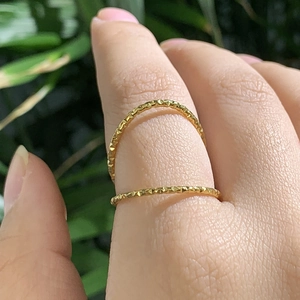 Set aus zwei goldenen Titanstahl-Ringen mit facettierter Textur auf grünem Hintergrund