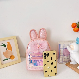 Pink sequin kids backpack with bunny ears and a large sheer bow in a cozy setting