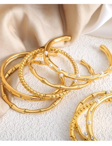 Detail showing 18k gold plated bracelets with bamboo, pearl, and zircon textured designs