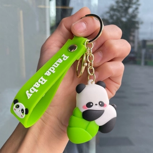 Close-up of a cute panda silicone keychain with green wrist strap and gold metal ring