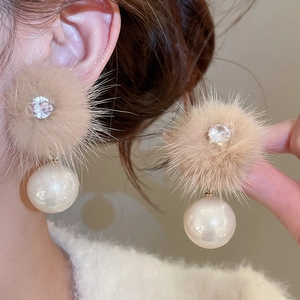 Detail of light coffee fur ball earrings with zircon accent and large pearl drop on ear