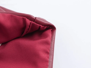 Gros plan sur la texture du cuir synthétique rouge foncé et la doublure du haut bustier