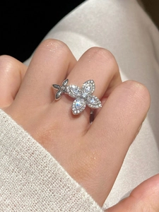 Detailed view of silver flower ring with white zircons worn on a model's finger