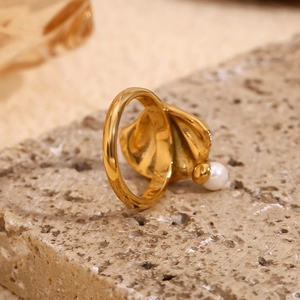 Close-up of 18K gold plated shell pearl ring with pavé diamonds on a stone base