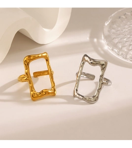 Close-up of gold and silver rectangle open rings with unique lava texture on white stone