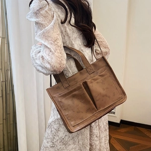 Λεπτομέρεια vintage καφέ τσάντα tote με μεγάλες τσέπες και διπλούς ιμάντες ώμου