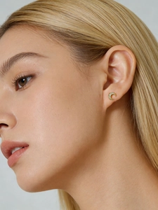 Close-up of a gold crescent moon earring set with cubic zirconia on a female model