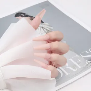 Gros plan d'ongles longs cercueil rose nude mats tenus avec du filet blanc