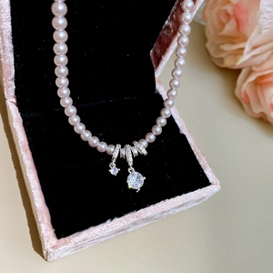 Vue macro d'un collier de perles roses avec pendentifs en cristal dans un écrin en velours