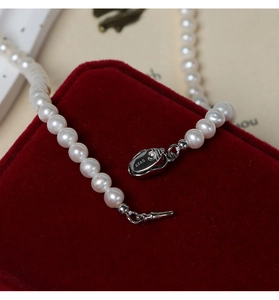 Macro view of white freshwater pearls and S925 sterling silver clasp on red velvet