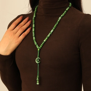 Green prayer beads necklace with star crescent pendant and tassel on a dark sweater