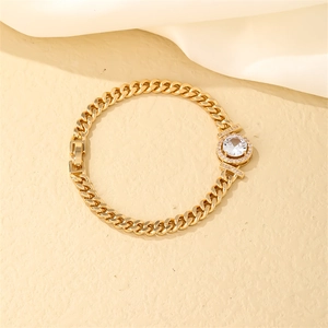 Detail of golden Cuban link bracelet with round zircon centerpiece and folded clasp
