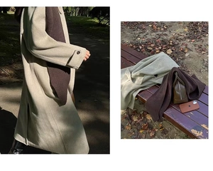 Detail view of a knitted dark brown scarf paired with a beige coat on a park bench