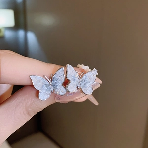 Detailed close-up of butterfly-shaped earrings with silver edges and white glittering texture
