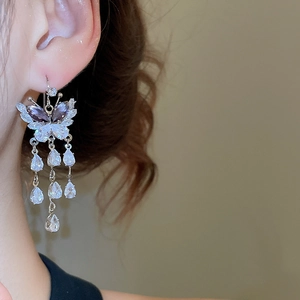 Macro detail of butterfly tassel earrings with purple crystals and silver fringe