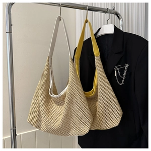 Detail view of woven straw tote bags in white and yellow hanging on a metal rack