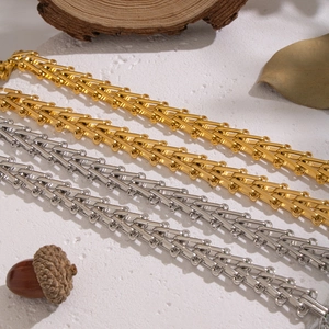 Waterproof gold and silver geometric woven chain necklaces on a rustic nature background