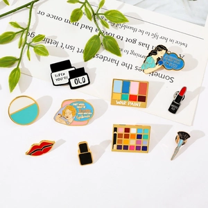 Detailed flat lay of makeup themed enamel pins with brushes and eyeshadow palettes