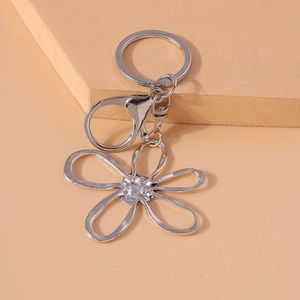 Elegant hollow flower keychain with silver lobster clasp and ring on beige background