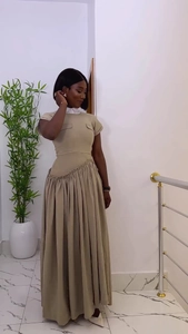 Detalle de vestido midi caqui con cintura plisada asimétrica y falda larga plisada