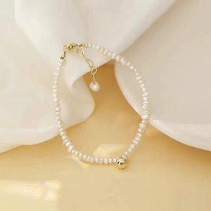 Detail of natural white freshwater pearl necklace with a polished gold bead and metal clasp