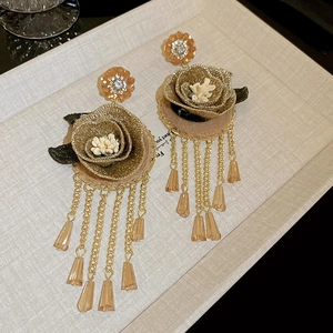Macro detail of vintage embroidered flower earrings with champagne gold tassels and beads